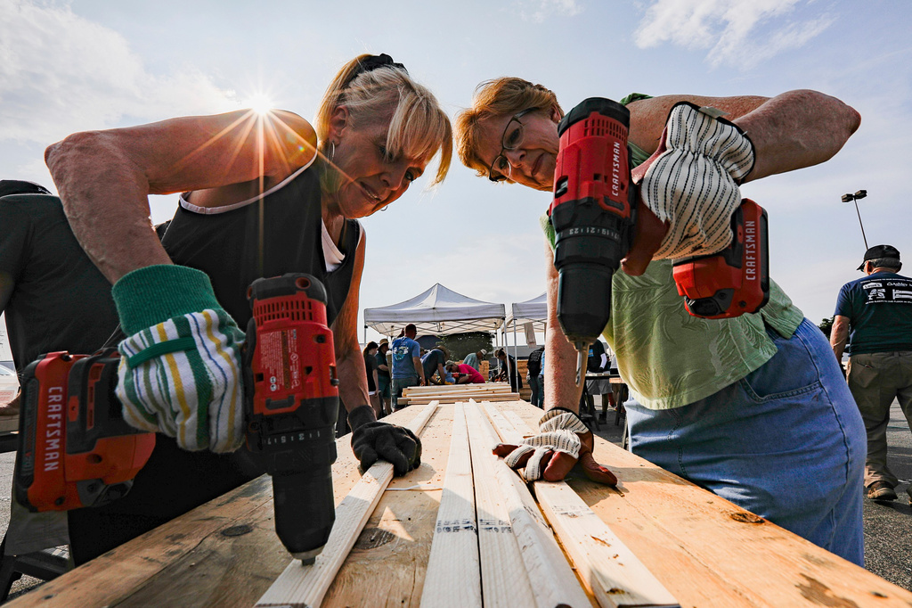 FILE - Volunteers Susan Chastain and Jenny Allen drill holes into two-by-fours during Bunks Across America, a non-profit event to build bunk beds for children in need at Lowe's, June 12, 2021 in East Brainerd, Tenn. (Troy Stolt/Chattanooga Times Free Press via AP, File)