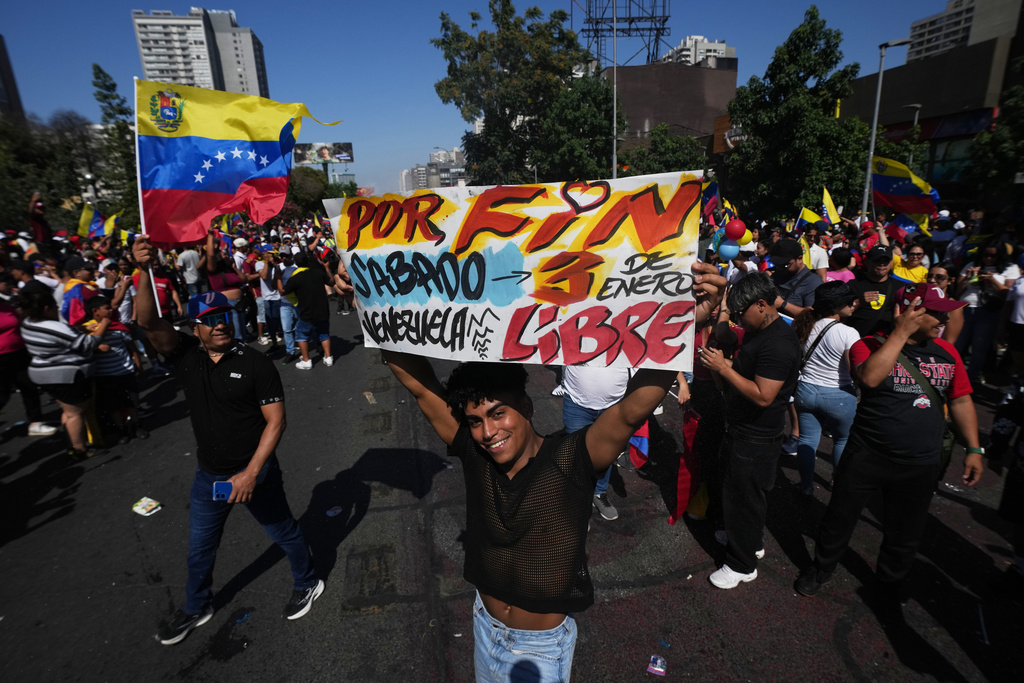 A Venezuelan celebrates holding a banner with a message that reads in Spanish: "At last Venezuela is free" after U.S. President Donald Trump announced that President Nicolas Maduro had been captured and flown out of Venezuela, in Santiago, Chile, Saturday, Jan. 3, 2026. (AP Photo/Esteban Felix)