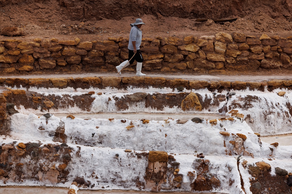 A man walks out to his family ponds at Salineras de Maras, Maras salt mines, in the Sacred Valley, near Cusco, Peru on Saturday, Aug. 30, 2025. (AP Photo/Alie Skowronski)