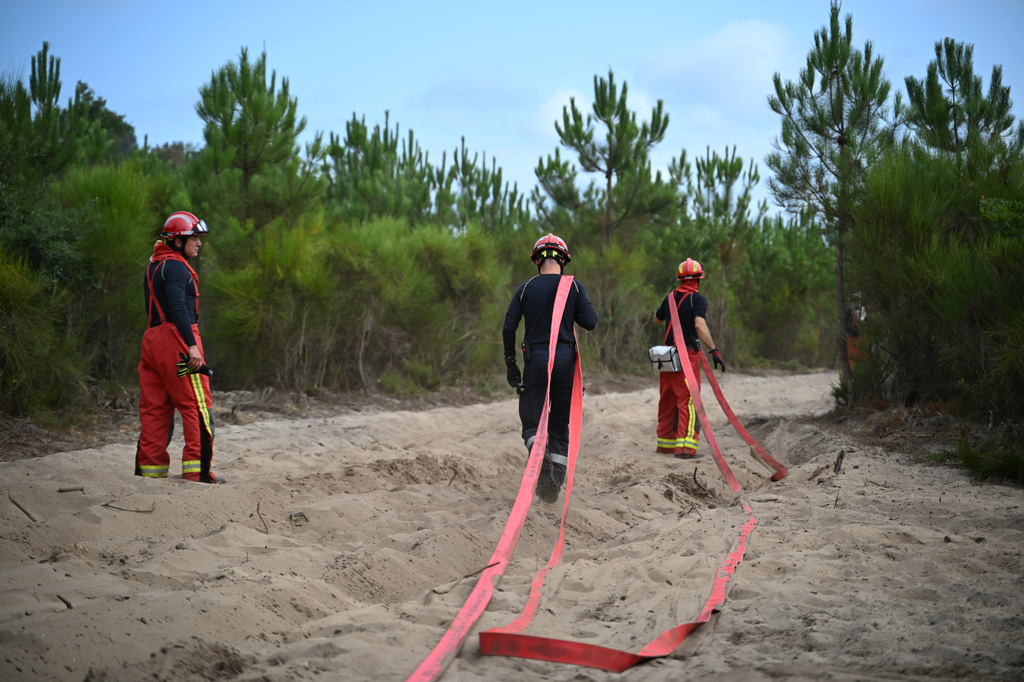 Firefighters pull hoses as they battle fires near Lege-Cap-Ferret, southwestern France, Friday, July 31, 2026. (AP Photo/Emma Da Silva)
