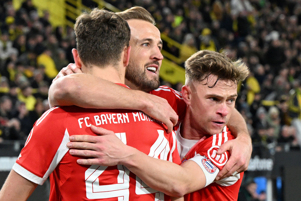 Bayern Munich's Harry Kane, center, celebrates scoring with Josip Stanisic and Joshua Kimmich, right, during the Bundesliga soccer match between Borussia Dortmund and FC Bayern Munich in Dortmund, Germany, Saturday Feb. 28, 2026. (Federico Gambarini/dpa via AP)
