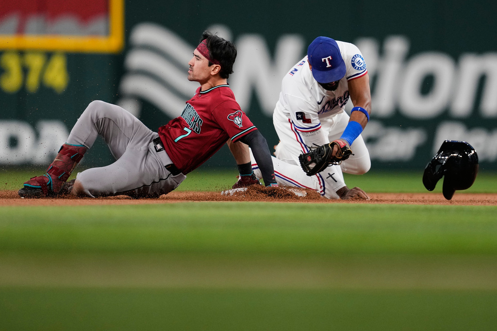 Arizona Diamondbacks' Corbin Carroll slides safely into second with a double as Texas Rangers second baseman Ezequiel Duran attempts to make the tag in the first inning of a baseball game Monday, May 11, 2026, in Arlington, Texas. (AP Photo/Tony Gutierrez)