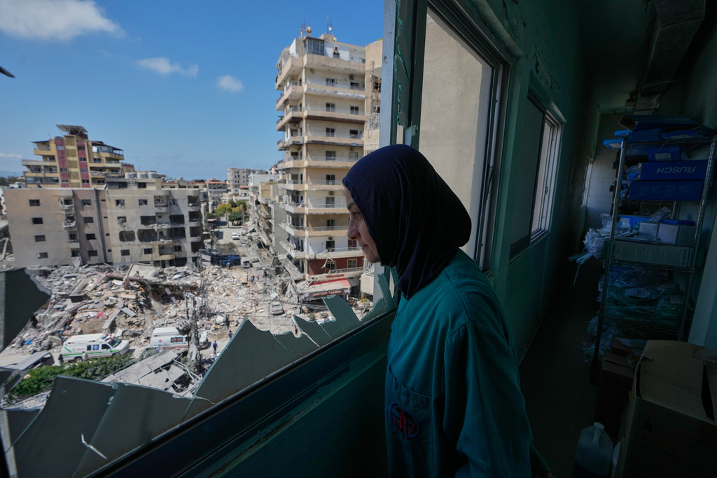 A nurse looks through a shattered window of the Jabal Amel Hospital into a destroyed building that was hit Monday in an Israeli airstrike, in the southern port city of Tyre, Lebanon, Tuesday, June 2, 2026. (AP Photo/Mohammed Zaatari)