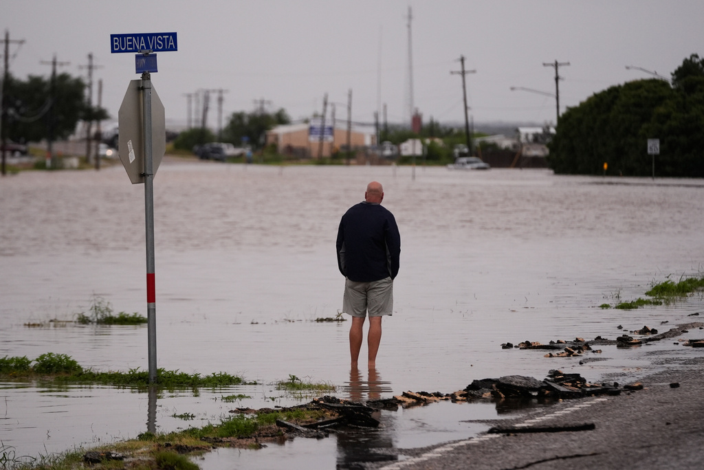 A man walks through flood waters on Friday, July 17, 2026, in Ozona, Texas. (AP Photo/Gerald Herbert)