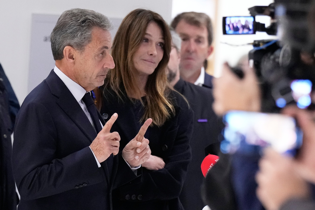 Former French President Nicolas Sarkozy, next to his wife Carla Bruni Sarkozy, speaks after a Paris court sentenced him to 5 years in prison and said he'll be incarcerated even if he appeals, after finding him guilty in his trial for alleged illegal campaign financing by Libya, Thursday, Sept. 25, 2025 in Paris. (AP Photo/Michel Euler)