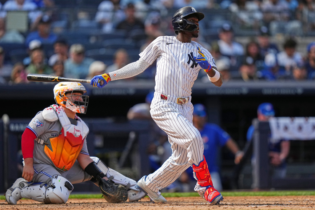 Toronto Blue Jays catcher Alejandro Kirk, left, watches as New York Yankees' Jazz Chisholm Jr. follows through on a single during the seventh inning of a baseball game Saturday, Aug. 22, 2026, in New York. (AP Photo/Frank Franklin II)