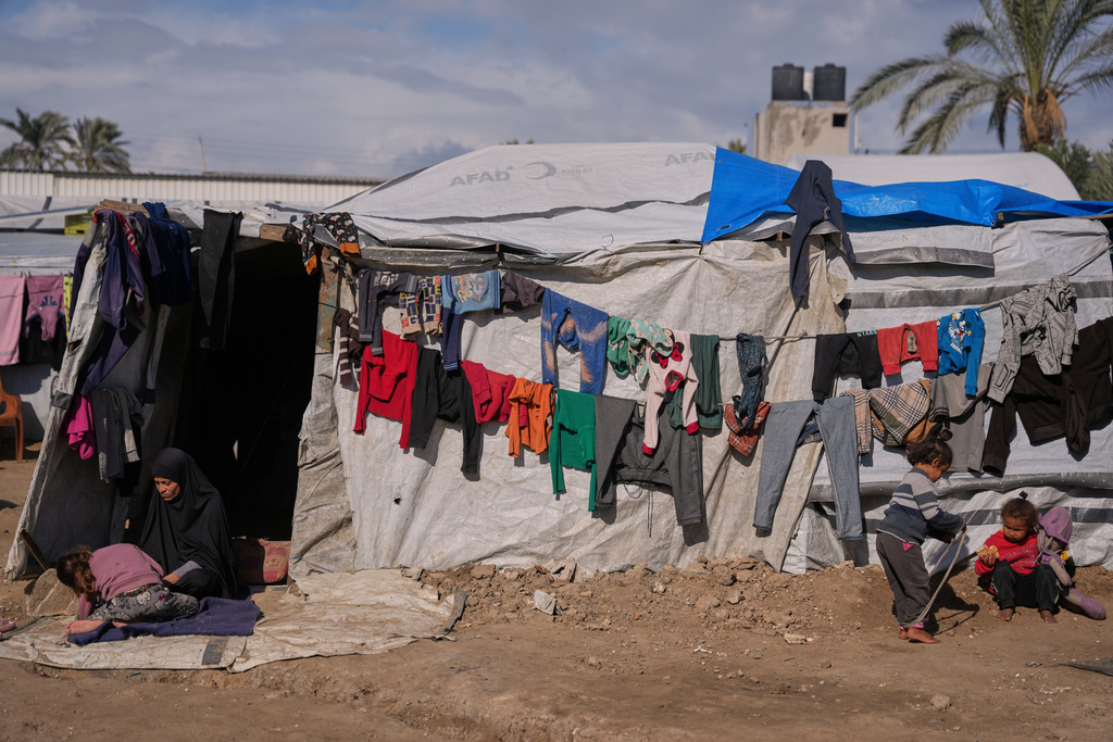 Reham Al-Helou, 35, sits at the entrance of her tent as her children play outside in a makeshift camp for displaced Palestinians in Deir al-Balah, central Gaza Strip, Saturday, Dec. 27, 2025. (AP Photo/Abdel Kareem Hana)