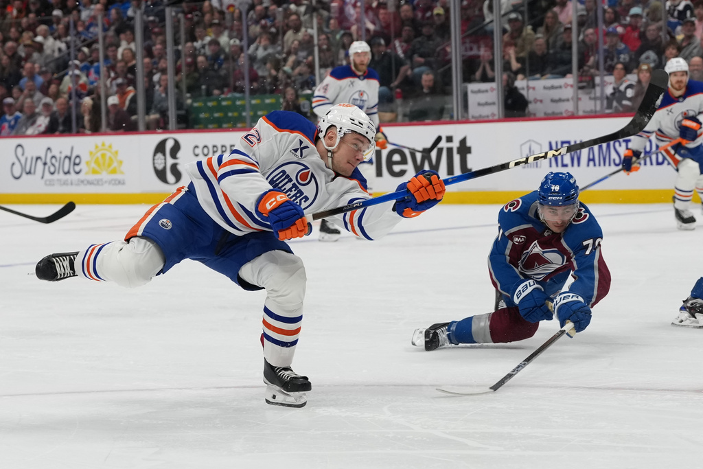 Edmonton Oilers right wing Vasily Podkolzin, front, shoots the puck as Colorado Avalanche defenseman Sam Malinski covers in the second period of an NHL hockey game Tuesday, March 10, 2026, in Denver. (AP Photo/David Zalubowski)