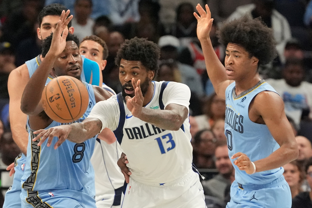 Dallas Mavericks forward Naji Marshall (13) passes the ball away from Memphis Grizzlies forward Jaren Jackson Jr. (8) and forward Jaylen Wells (0) during the first half of an NBA Cup basketball game Friday, Nov. 7, 2025, in Memphis, Tenn. (AP Photo/George Walker IV)