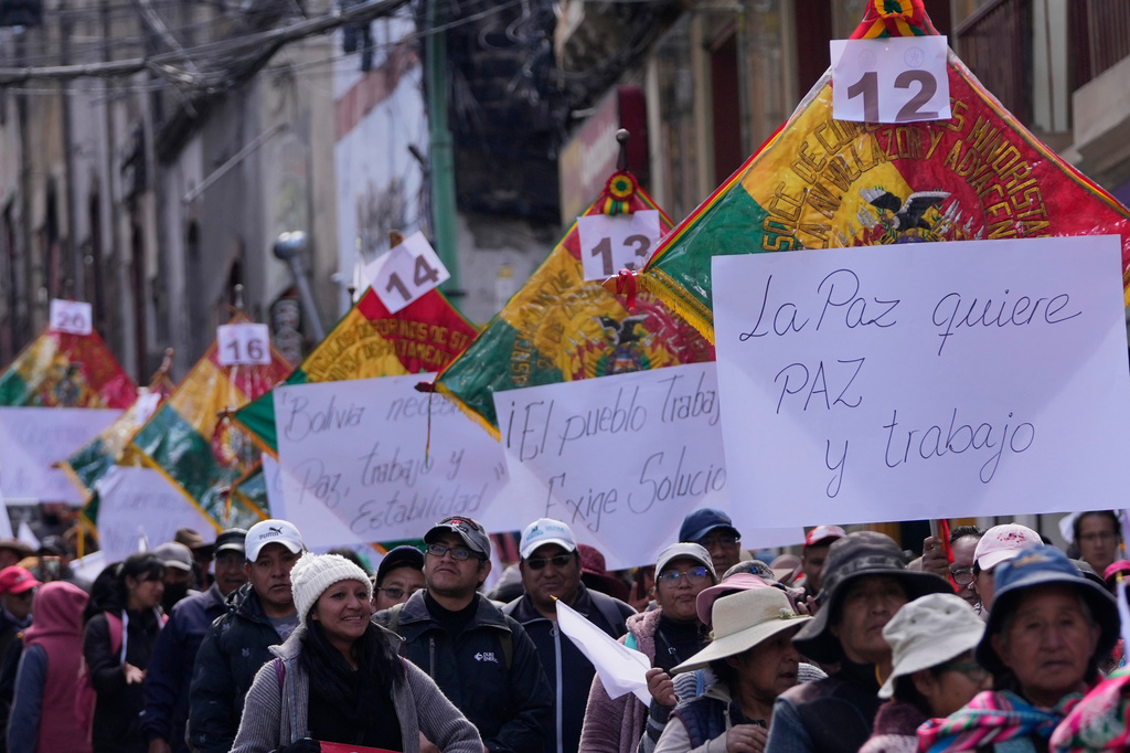 Vendors hold signs reading in Spanish, "La Paz wants peace and work," during a march against protesters who were blocking access to the city, in La Paz, Bolivia, Tuesday, May 26, 2026. (AP Photo/Juan Karita)