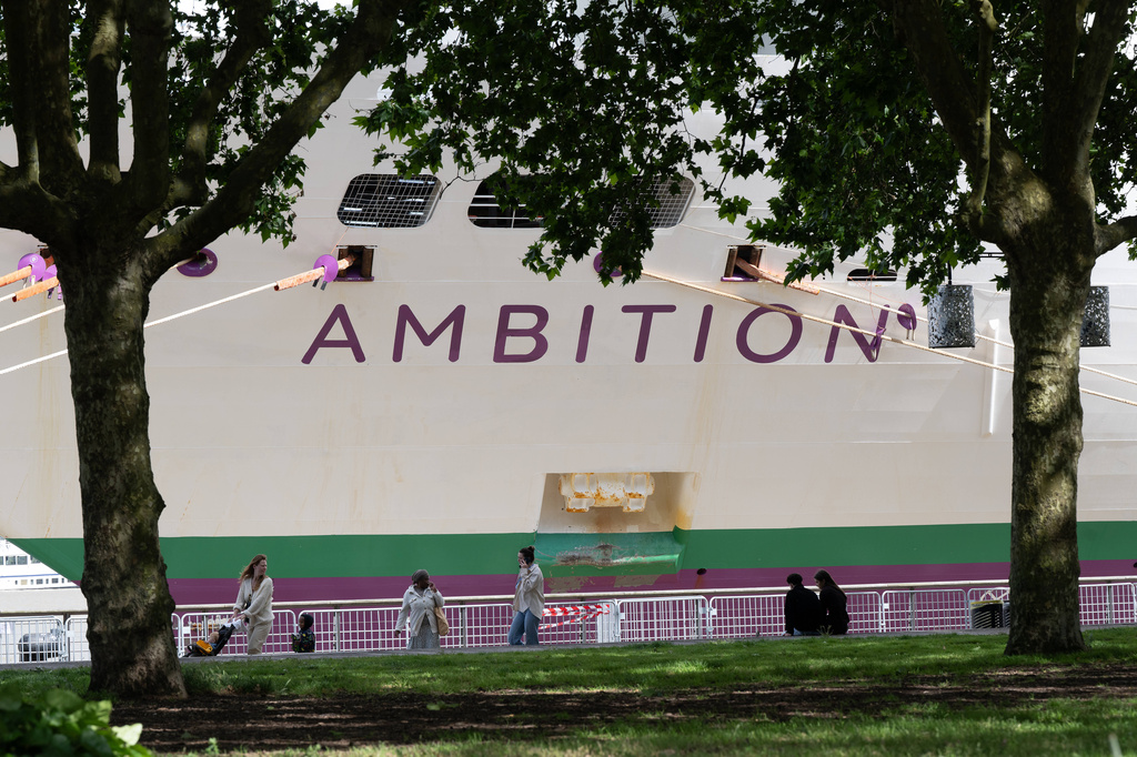 People walk past the British cruise ship Ambition as French authorities have ordered 1,700 passengers and crew to stay on board due to a gastrointestinal illness outbreak, in Bordeaux, southwestern France, Wednesday, May 13, 2026. (AP Photo/Caroline Blumberg)