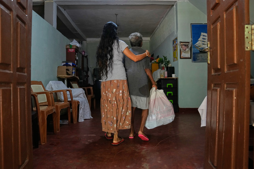 A worker helps a fire survivor at a nursing home, where inmates of another nursing home that caught fire on Wednesday are being temporarily housed, in Anguruwatota, Sri Lanka, Friday, June 5, 2026. (AP Photo/Eranga Jayawardena)
