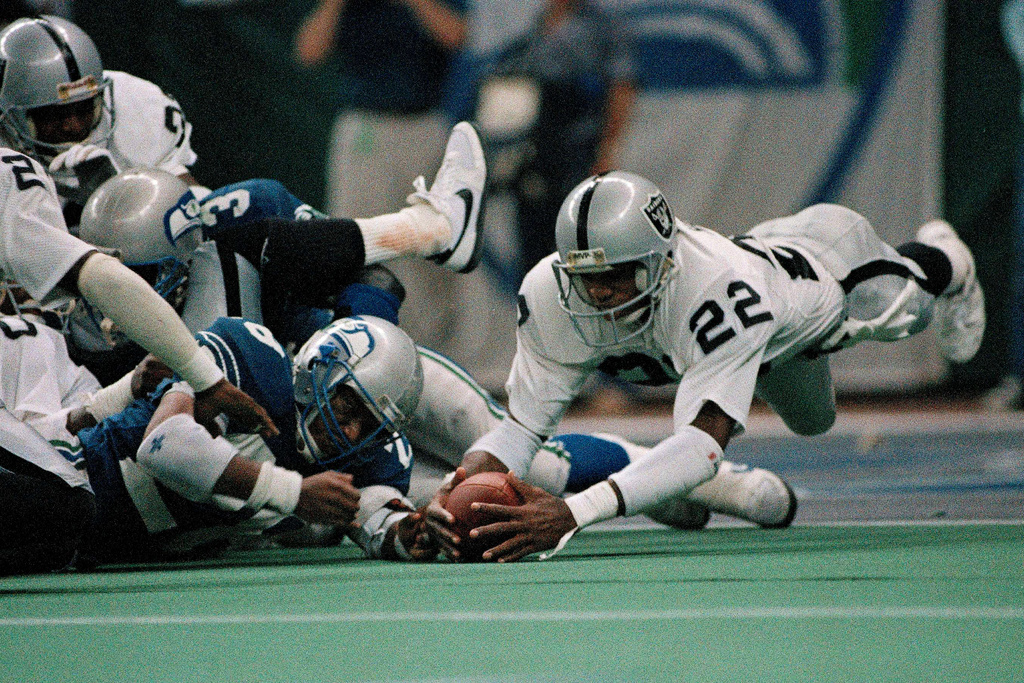 FILE - Los Angeles Raiders Mike Haynes (22) of the dives to grab a fumble by Seattle Seahawks quarterback Curt Warner, left, during the fourth quarter of an NFL football game in Seattle, Nov. 29, 1988. (AP Photo/Barry Sweet, File)