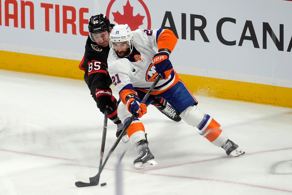 Ottawa Senators defenseman Jake Sanderson (85) pressures New York Islanders center Kyle Palmieri (21) during the first period of an NHL hockey game in Ottawa, Ontario, Saturday, Oct. 18, 2025. (Adrian Wyld/The Canadian Press via AP)