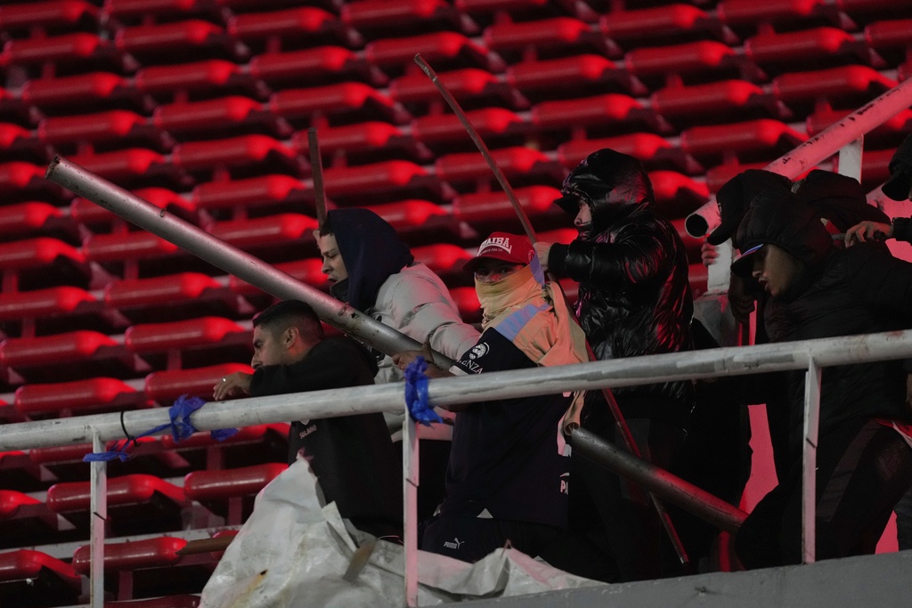 Fans of Argentina's Independiente hold metal bars during clashes with Universidad de Chile fans after a Copa Sudamericana round of sixteen second leg soccer match was suspended at the Libertadores de America stadium in Avellaneda, Argentina, Wednesday, Aug. 20, 2025. (AP Photo/Gustavo Garello)