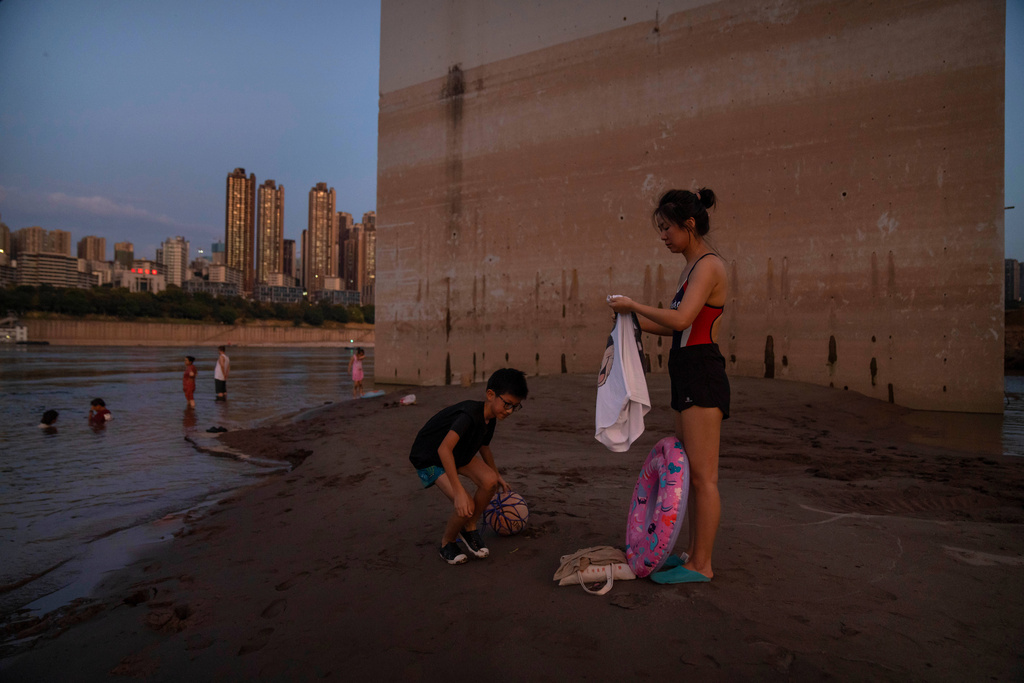 FILE - People prepare to swim in the Yangtze River near a bridge support column that shows previous water levels in southwestern China's Chongqing Municipality, Aug. 19, 2022. (AP Photo/Mark Schiefelbein, File)