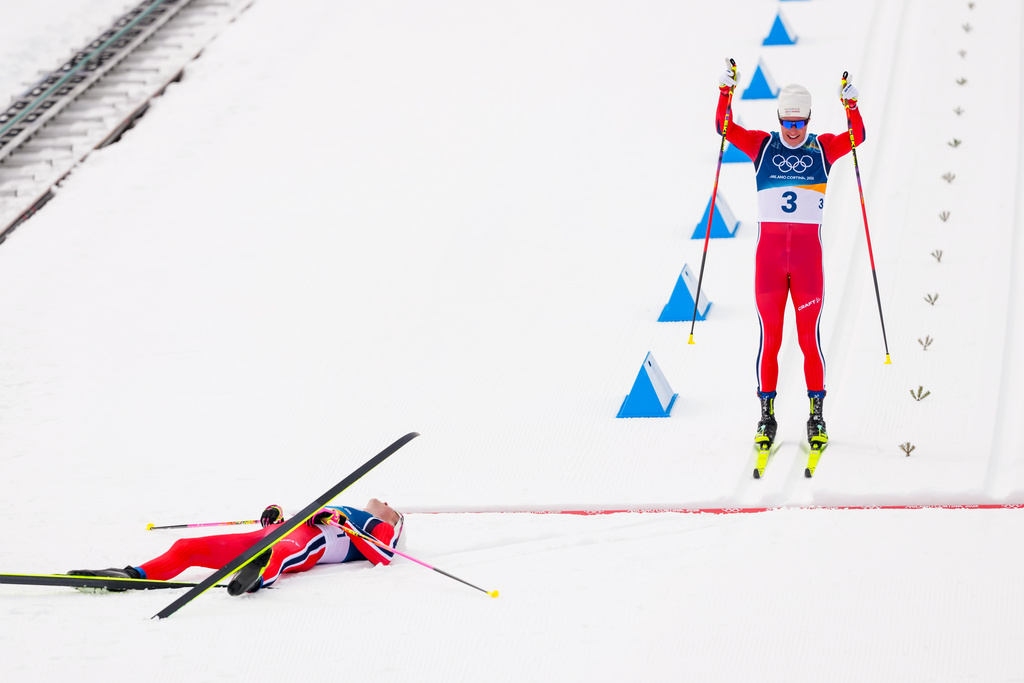 Martin Loewstroem Nyenget, of Norway, crosses the finish line to win the silver medal, behind Johannes Hoesflot Klaebo, also of Norway, in the cross country skiing men's 50km mass start Classic at the 2026 Winter Olympics, in Tesero, Italy, Saturday, Feb. 21, 2026. (AP Photo/Kirsty Wigglesworth)