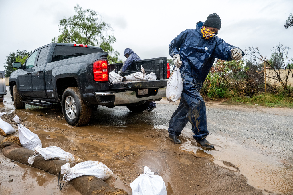 James Jones places a sandbag to prevent water from running off a property scorched in the Eaton Fire in Altadena, Calif., as the region remains under flash flood warnings on Saturday, Nov. 15, 2025. (AP Photo/Noah Berger)