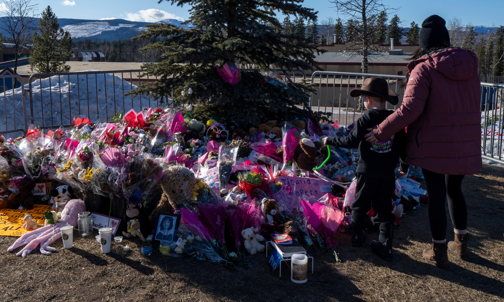 FILE - A mother and son pay their respects at a memorial for the victims of a mass shooting in Tumbler Ridge, British Columbia, Canada, Feb. 14, 2026. (Christinne Muschi/The Canadian Press via AP, File)