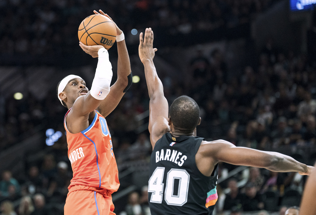Oklahoma Thunder guard Shai Gilgeous-Alexander (2) shoots over the reach of San Antonio Spurs forward Harrison Barnes (40) during the first half of an NBA basketball game in San Antonio, Tuesday, Dec. 23, 2025. (AP Photo/Rodolfo Gonzalez)