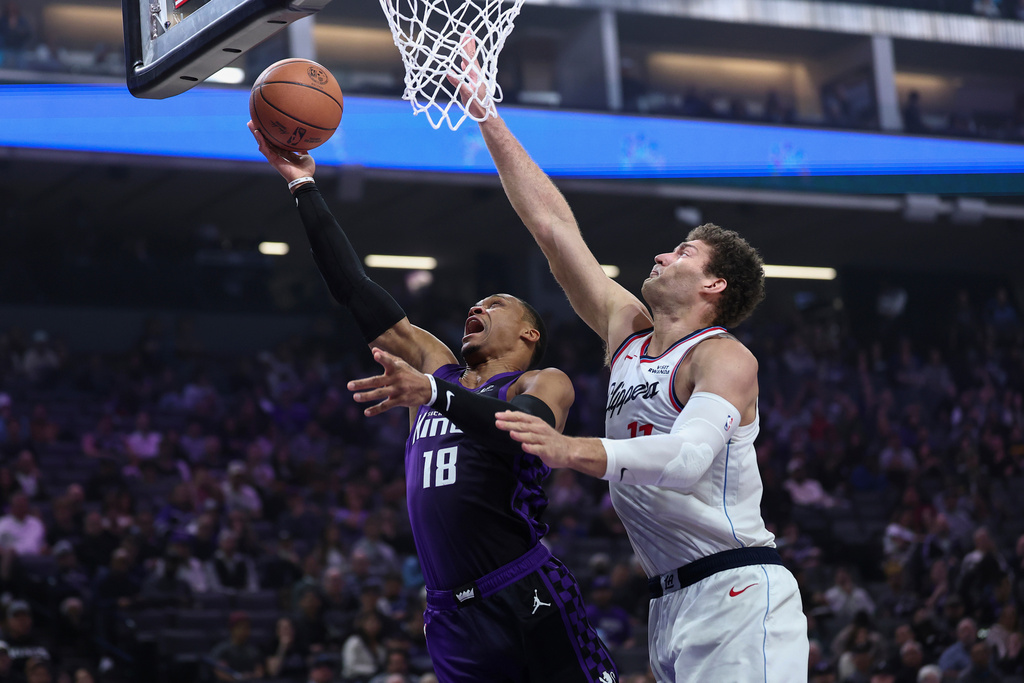 Sacramento Kings guard Russell Westbrook (18) draws the foul on Los Angeles Clippers center Brook Lopez, right, during the first half of an NBA basketball game Friday, Feb. 6, 2026, in Sacramento, Calif. (AP Photo/Sara Nevis)