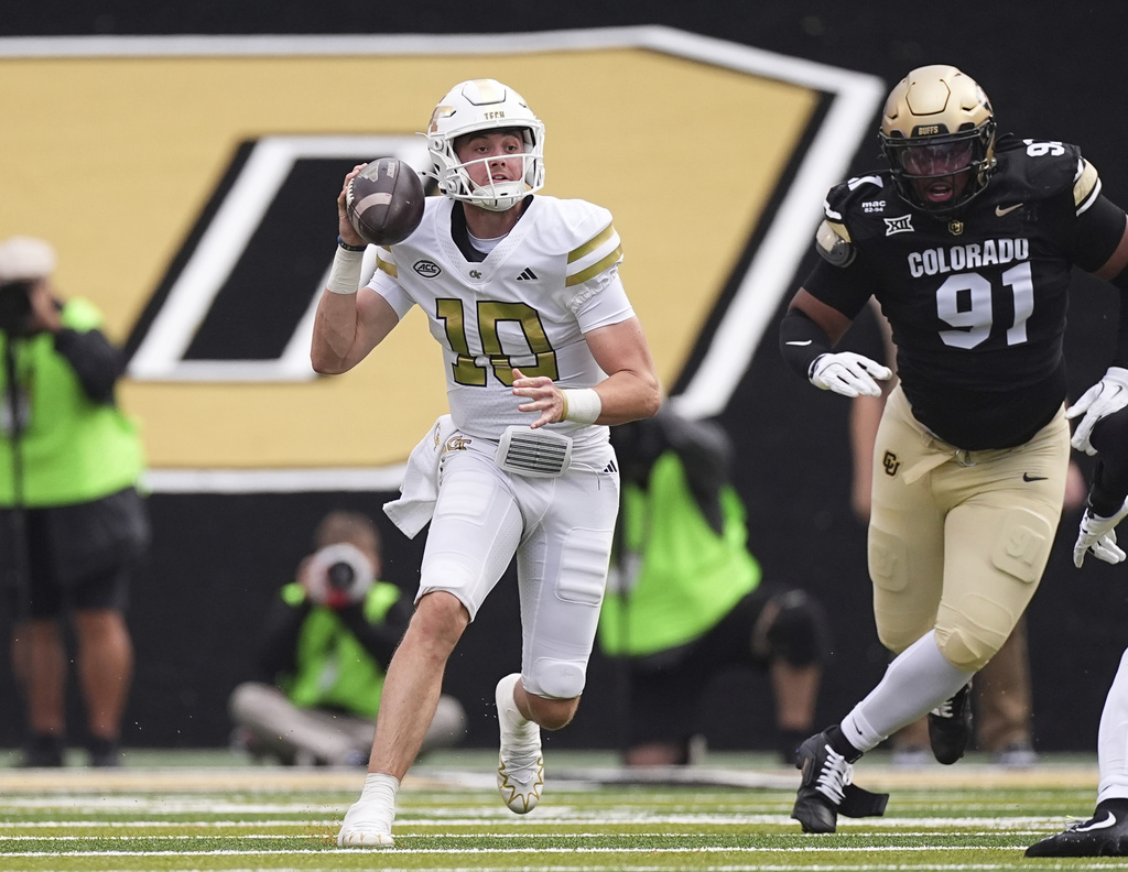 Georgia Tech quarterback Haynes King, left, looks to pass the ball as Colorado defensive end Brandon Davis-Swain pursues in the first half of an NCAA college football game Friday, Aug. 29, 2025, in Boulder, Colo. (AP Photo/David Zalubowski)