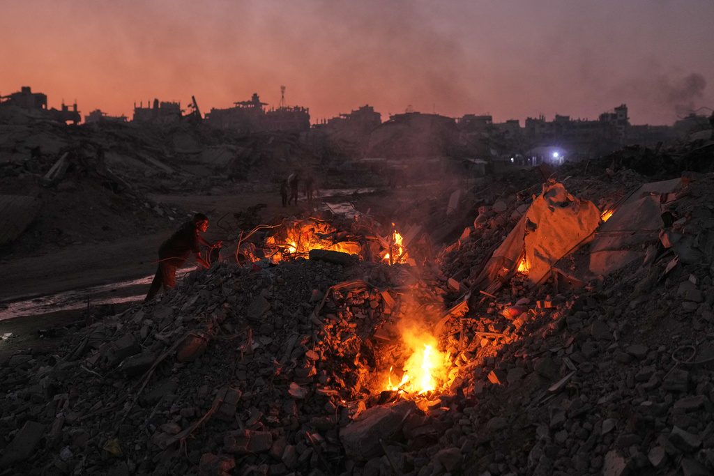 Palestinians light fires to keep away mosquitoes amid the destruction left by Israeli air and ground offensive in the Sheikh Radwan neighborhood of Gaza City, Monday, Nov. 10, 2025. (AP Photo/Jehad Alshrafi)