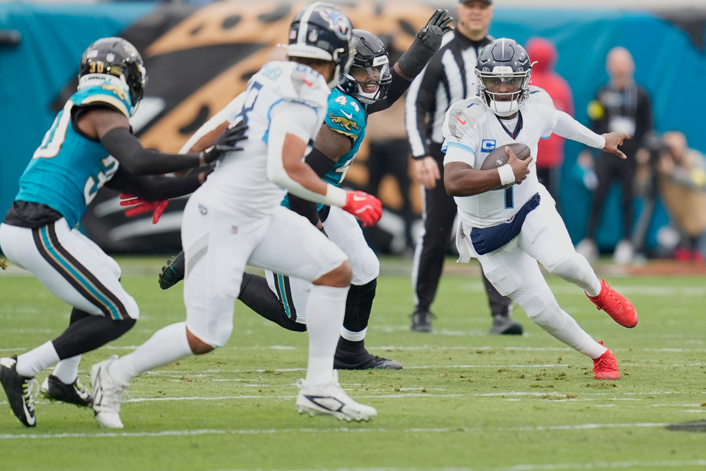 Tennessee Titans quarterback Cam Ward (1) runs the ball past Jacksonville Jaguars defensive end Travon Walker (44) during the first half of an NFL football game Sunday, Jan. 4, 2026, in Jacksonville, Fla. (AP Photo/John Raoux)