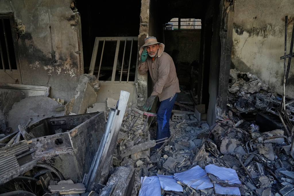A volunteer talks on his phone while walking amid the debris of a residential building that, according to the authorities, was damaged on March 4 during the U.S.-Israeli military campaign, in southeastern Tehran, Iran, Tuesday, April 14, 2026. (AP Photo/Vahid Salemi)