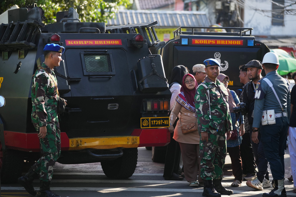 Curious onlookers look on as military personnel stand guard near a school where explosions reportedly occurred, in Jakarta, Indonesia, Friday, Nov. 7, 2025. (AP Photo/Dita Alangkara)