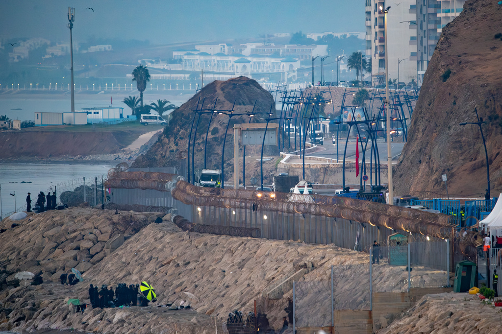 Morocco security forces, bottom left, patrol the Spanish-Moroccan border seen from the Spanish enclave of Ceuta, Saturday, Aug. 15, 2026. (AP Photo/Antonio Sempere)