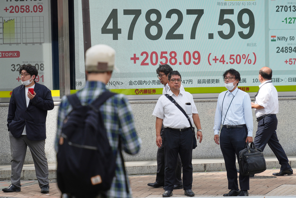 People stand in front of an electronic stock board showing Japan's Nikkei index at a securities firm Monday, Oct. 6, 2025, in Tokyo. (AP Photo/Eugene Hoshiko)