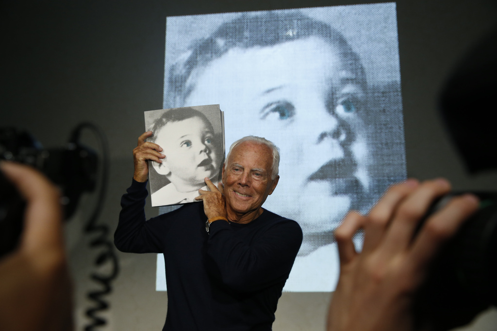 FILE - Italian fashion designer Giorgio Armani poses for photographers holding a copy of the book, 'Giorgio Armani' written by journalist Suzy Menkes, presented at the end his women's Spring-Summer 2016 collection, during fashion week in Milan, Italy, Sept. 28, 2015. (AP Photo/Luca Bruno, File)