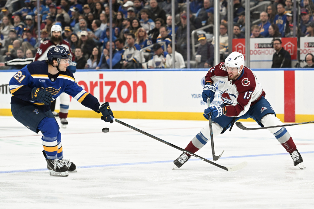 Colorado Avalanche's Valeri Nichushkin (13) makes a pass past St. Louis Blues' Jimmy Snuggerud (21) during the third period of an NHL hockey game, Tuesday, April 7, 2026, in St. Louis. (AP Photo/Joe Puetz)