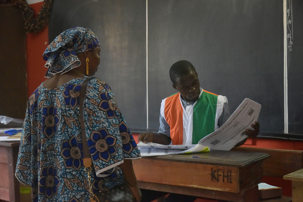 A woman checks her name at the register during the Presidential elections in Cocody, Ivory coast, Saturday, Oct. 25, 2025, (AP Photo/Diomande Ble Blonde)