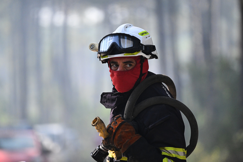 A firefighter carries his equipment as he works to suppress a fire in a forest in Claouey, during wildfires in the area of southwestern France, Tuesday, July 28, 2026. (AP Photo/Emma Da Silva)