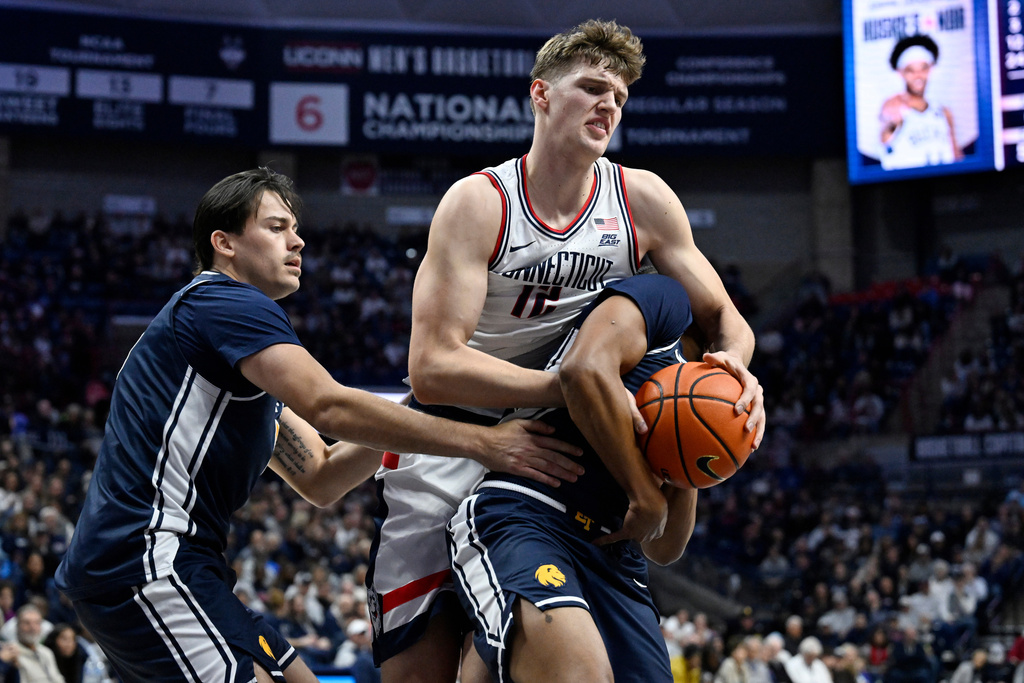 UConn's Eric Reibe, top right, fights for control of the ball over East Texas A&M's Evan Phelps, bottom right, as East Texas A&M's Tay Mosher, left, defends in the first half of an NCAA college basketball game, Friday, Dec. 5, 2025, in Storrs, Conn. (AP Photo/Jessica Hill)