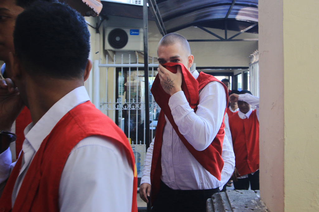 Swiss tourist Luzian Andrin Zgraggen who is accused of insulting the Balinese Hinduism's sacred Day of Silence in social media posts covers his face upon arrival at the district court in Denpasar, Bali, Indonesia, Thursday, Aug. 20, 2026. (AP Photo)
