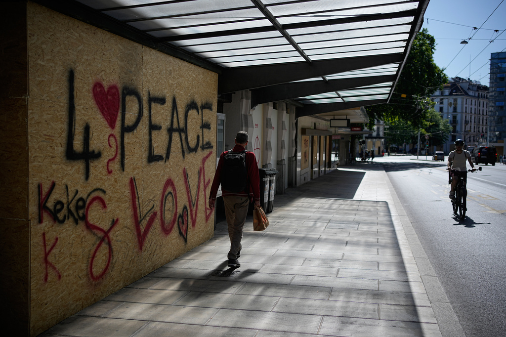 People pass by broken coffee shop windows the day after a demonstration against the G7 summit in Geneva, Switzerland, Monday, June 15, 2026. (AP Photo/Laurent Cipriani)