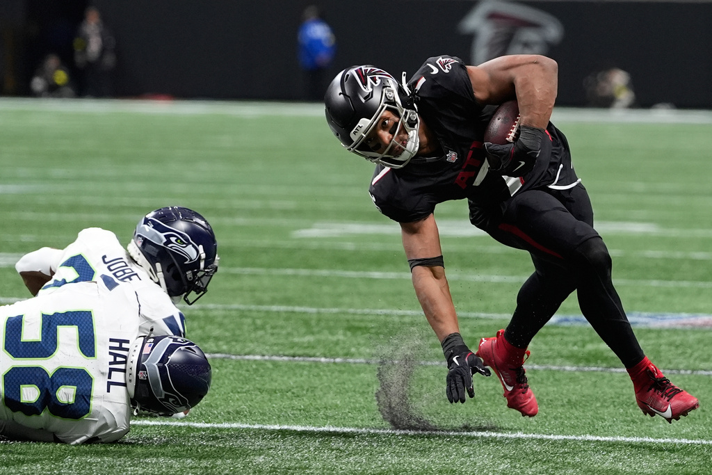 Atlanta Falcons running back Bijan Robinson (7) avoids tackles from Seattle Seahawks linebacker Derick Hall (58) and cornerback Josh Jobe (29) during the first half of an NFL football game, Sunday, Dec. 7, 2025, in Atlanta. (AP Photo/Brynn Anderson)