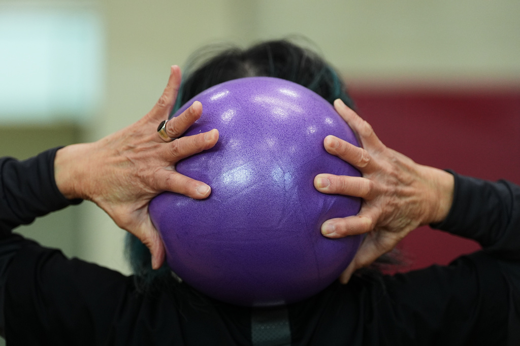 A participant grabs an exercise ball during a class for older adults led by instructor Bengie Santos at the Dale Turner Family YMCA, April 30, 2026, in Shoreline, Wash. (AP Photo/Lindsey Wasson)
