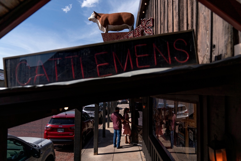 FILE - A bull statue stands atop a steakhouse restaurant as a couple walks in for dinner in Fort Worth, Texas, April 21, 2023. (AP Photo/David Goldman, File)