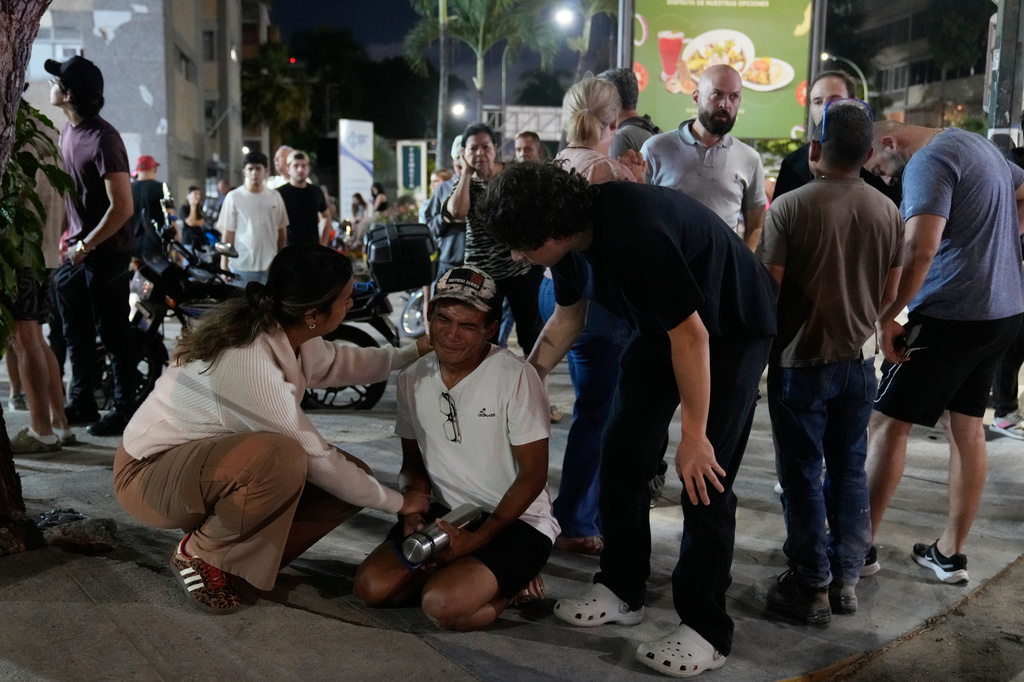 Residents console a man outside their homes after successive earthquakes, in Caracas, Venezuela, Wednesday, June 24, 2026. (AP Photo/Ariana Cubillos)