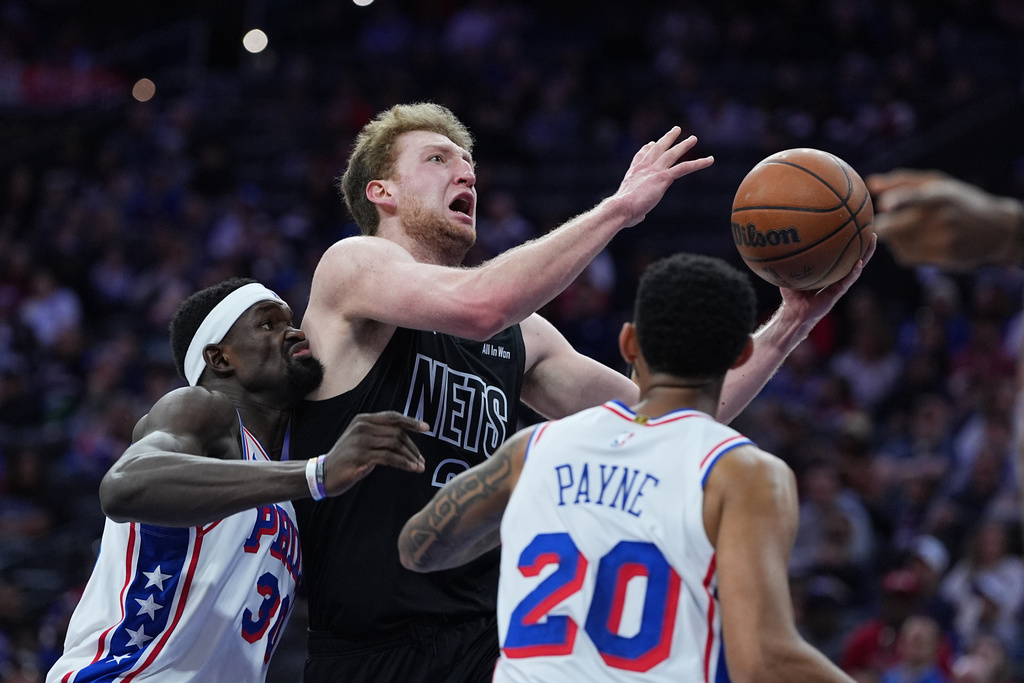 Brooklyn Nets' Danny Wolf, center, shoots between Philadelphia 76ers' Adem Bona, left, and Cameron Payne (20) during the first half of an NBA basketball game Saturday, March 14, 2026, in Philadelphia. (AP Photo/Matt Rourke)