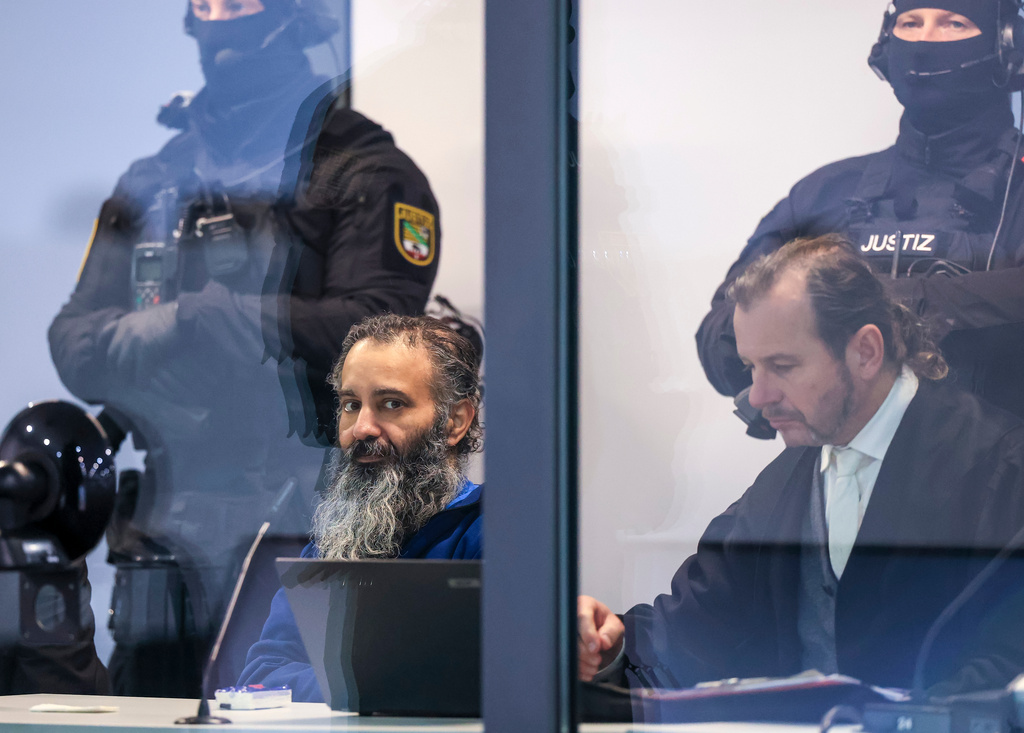 The defendant Taleb al-Abdulmohsen, left, sits next to his defense lawyer Thomas Rutkowski in a bullet-proof glass box for the continuation of the trial in the temporary court building of the Magdeburg Regional Court, Germany, Thursday, Nov. 20, 2025. (Jan Woitas/dpa via AP)