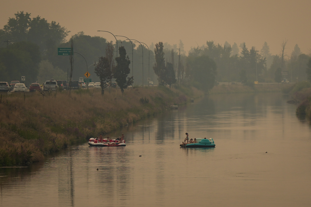 People float on the Channel Pathway that connects Okanagan Lake and Skaha Lake as smoke from wildfires burning in the region fills the air, in Penticton, British Columbia, Monday, Aug. 10, 2026. (Darryl Dyck/The Canadian Press via AP)