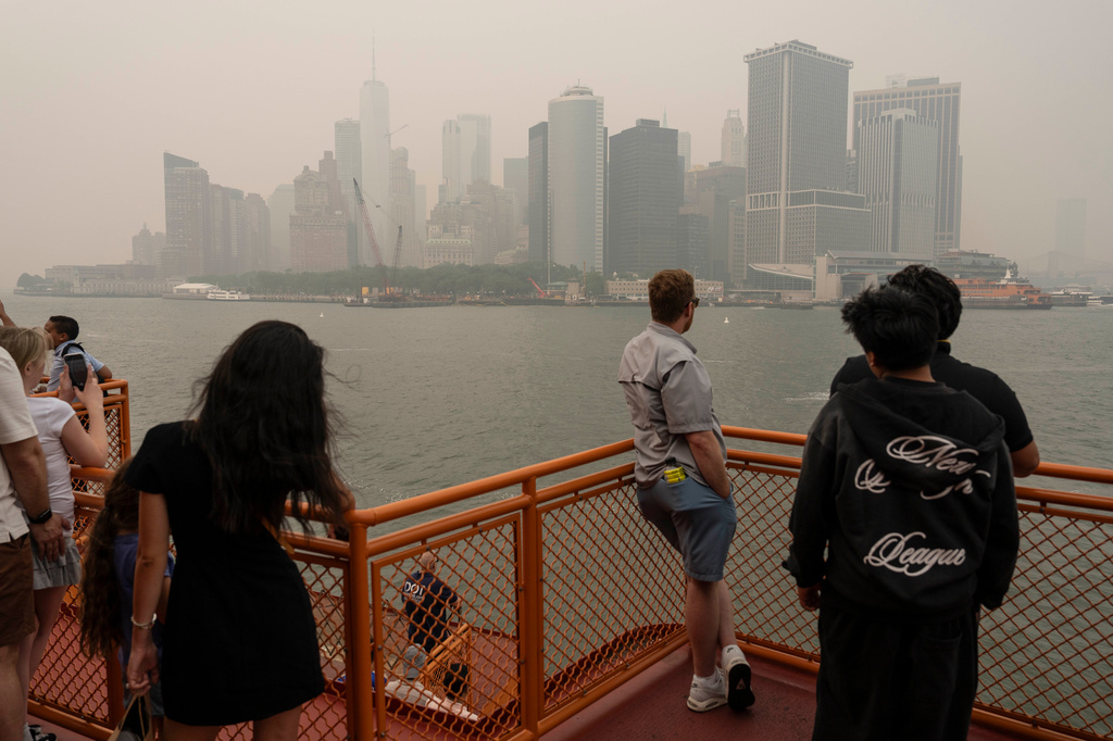 People take the Staten Island Ferry as smoke from wildfires blankets the sky, Thursday, July 16, 2026, in New York. (AP Photo/Yuki Iwamura)