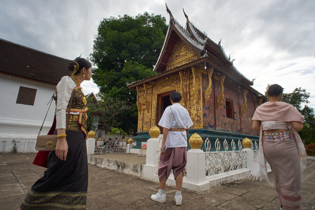 Visitors wearing traditional Lao dress arrive at a gilded Buddhist temple in Luang Prabang, Laos, to pay respects and explore the historic complex on Sunday, Nov. 2, 2025. (AP Photo/Eugene Hoshiko)