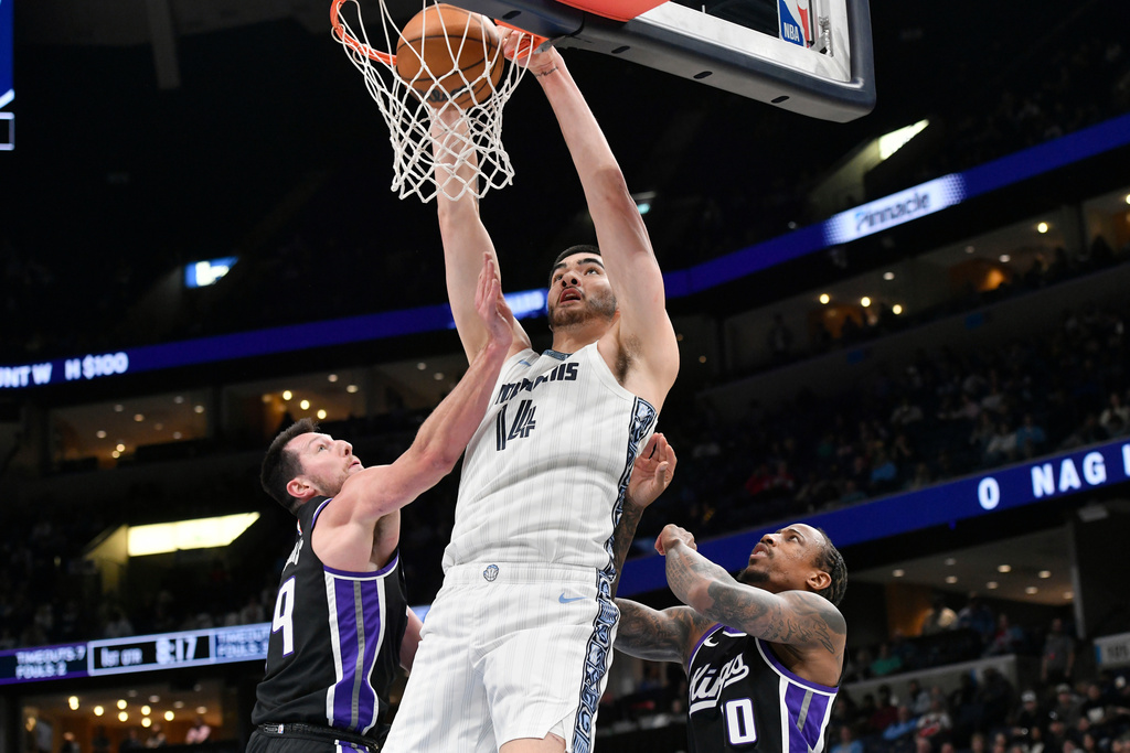 Memphis Grizzlies center Zach Edey (14) dunks over Sacramento Kings forward Drew Eubanks (19) and guard DeMar DeRozan (10) in the first half of an NBA basketball game, Thursday, Nov. 20, 2025, in Memphis, Tenn. (AP Photo/Brandon Dill)