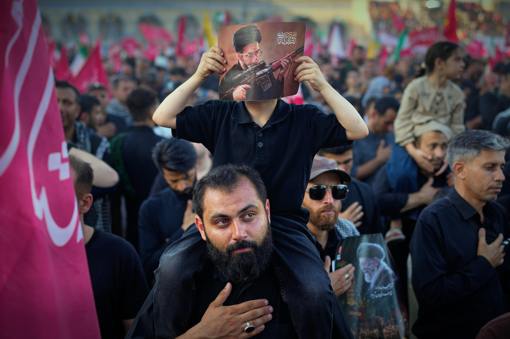 A boy holds a picture of Iran's new Supreme Leader, Mojtaba Khamenei, holding a machine gun at the Imam Khomeini Mosalla Grand Mosque during funeral ceremonies for the slain Iranian Supreme Leader Ayatollah Ali Khamenei and members of his family in Tehran, Iran, Sunday, July 5, 2026. (AP Photo/Altaf Qadri)